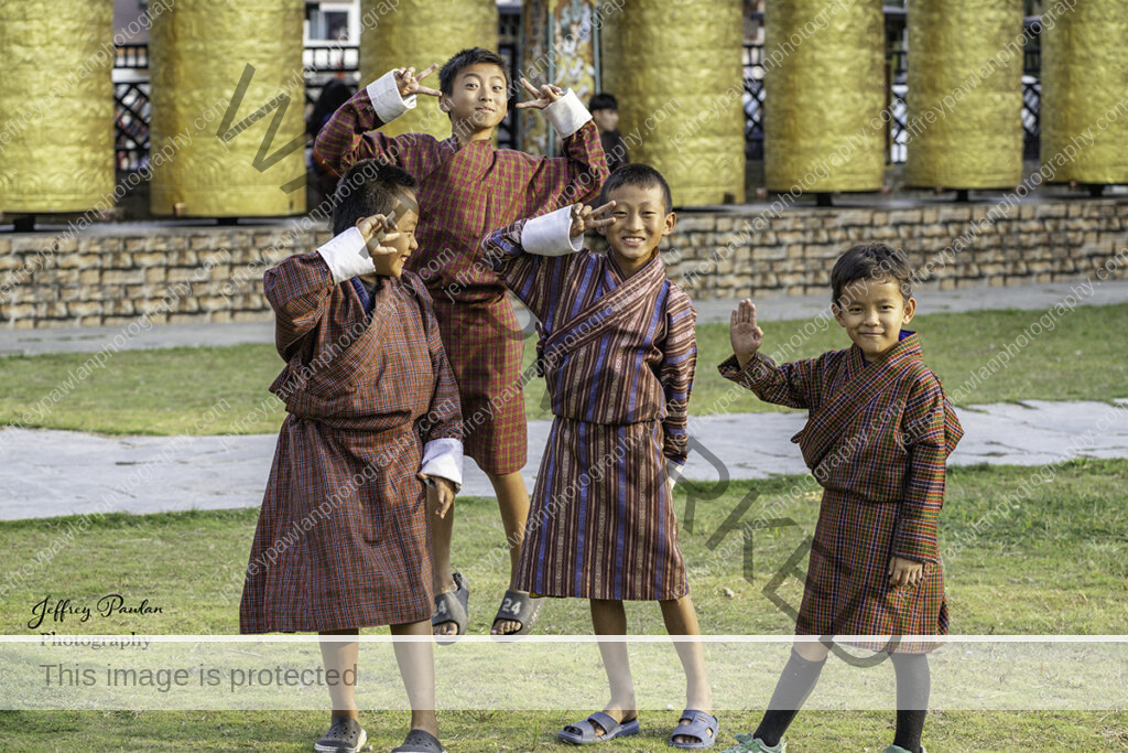 920565-Bhutan-boys-having-fun-in-front-of-the-prayer-wheels-signed-WP-1-1024x683